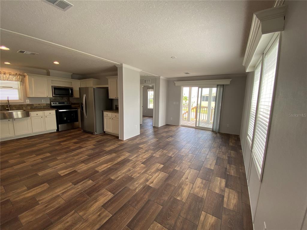 An open-concept kitchen and living area with wood-look tile flooring and sliding glass doors — 538 FLEETWOOD STREET, NORTH PORT, FL