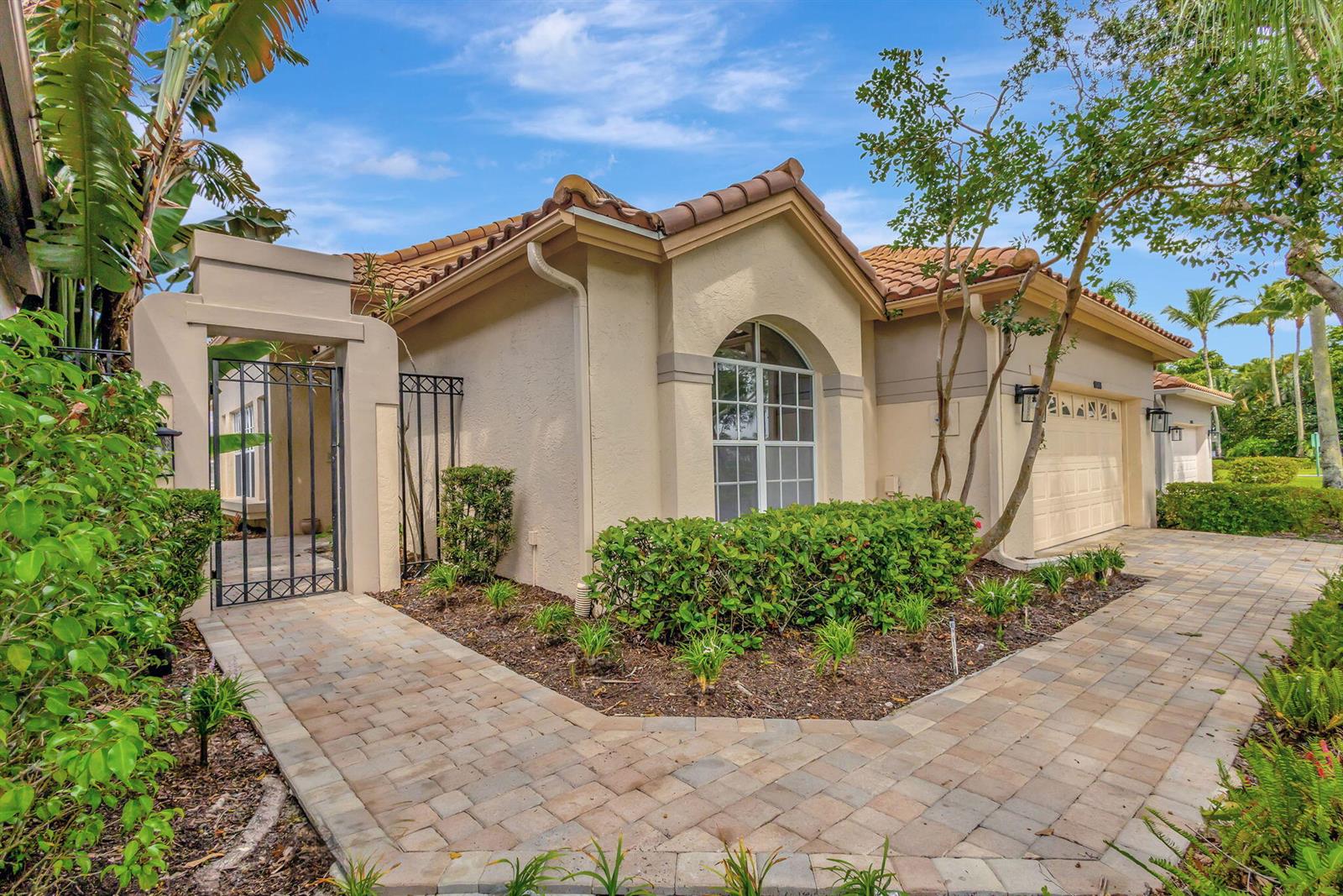 A single-story house with a tiled roof, beige stucco walls, and a paved walkway entrance — 10414 Osprey Trace, West Palm Beach FL 33412, WEST PALM BEACH, FL