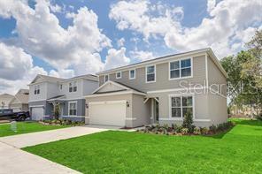 A two-story suburban house with light gray siding, a two-car garage, and a green lawn — 5614 OAK KNOLL DRIVE, ST CLOUD, FL