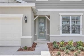 A view of a house exterior featuring a garage, a front door, and a window — 5614 OAK KNOLL DRIVE, ST CLOUD, FL