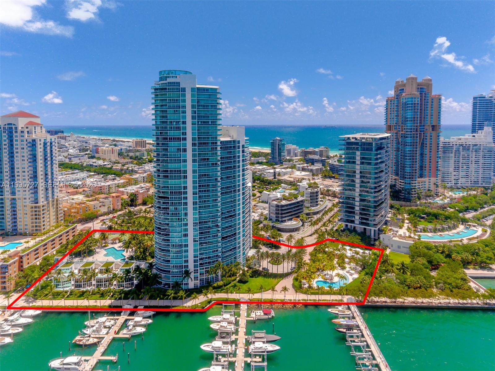 An aerial view shows a high-rise residential complex with a pool and marina — 1000 S Pointe dr # 906, Miami Beach FL 33139, MIAMI BEACH, FL