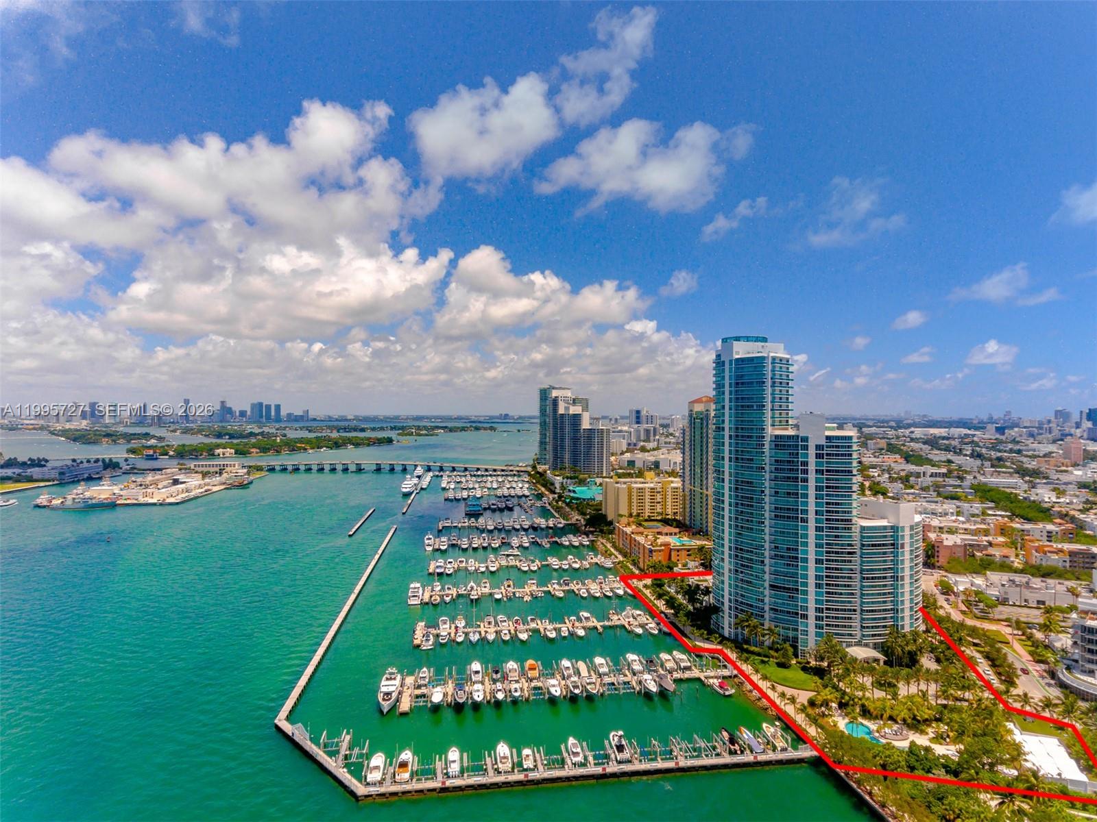 An aerial view shows a high-rise residential building with a private marina and boat slips — 1000 S Pointe dr # 906, Miami Beach FL 33139, MIAMI BEACH, FL