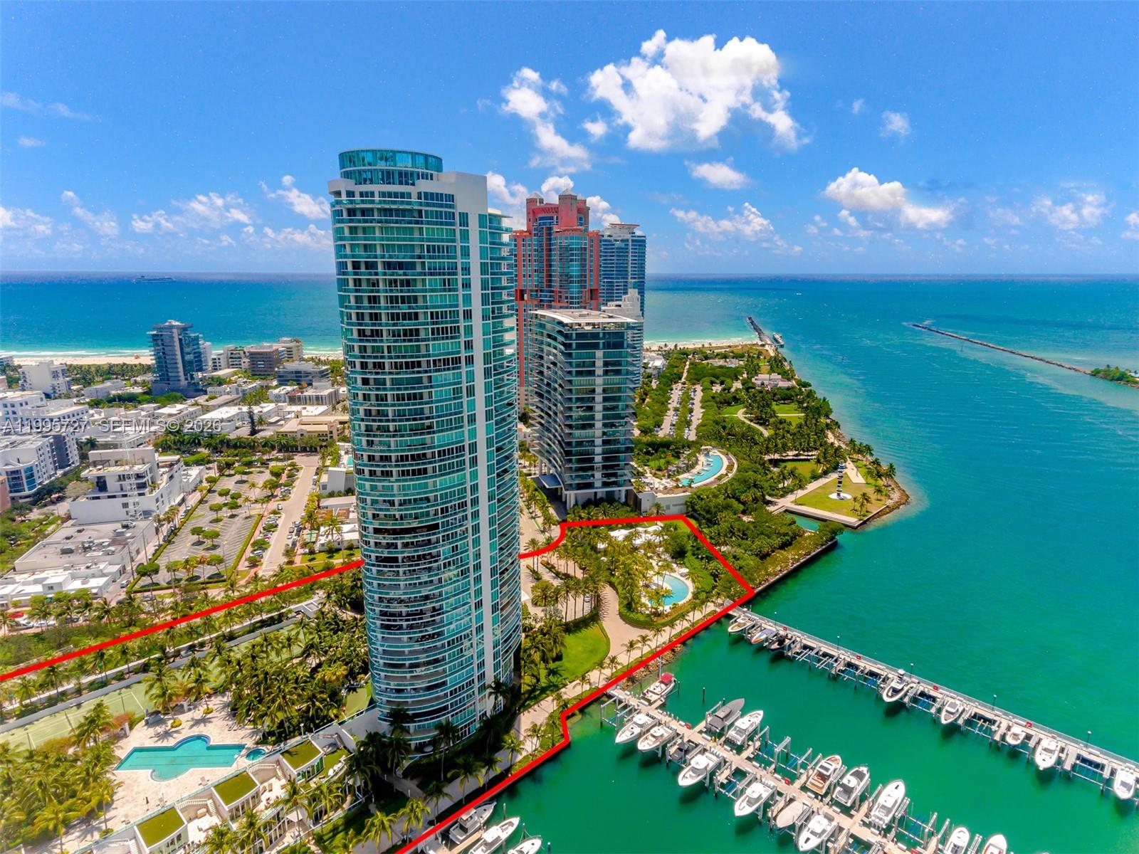 An aerial view shows a tall residential tower, a marina, and a waterfront park — 1000 S Pointe dr # 906, Miami Beach FL 33139, MIAMI BEACH, FL