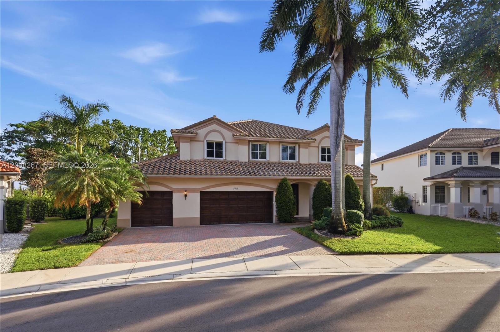 A two-story suburban house features a tiled roof, a three-car garage, and palm trees — 1419 Crossbill Ct # 1419, Weston FL 33327, WESTON, FL