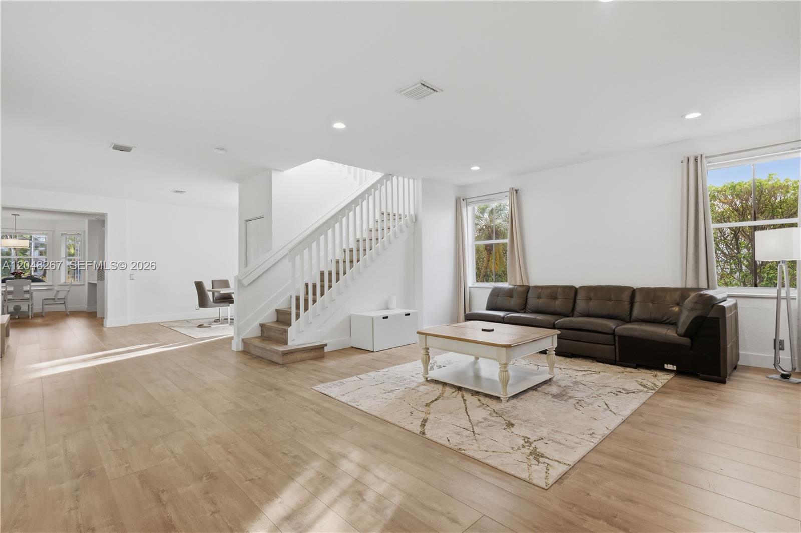 A living room features light wood flooring, a staircase, and a dark leather sectional sofa — 1419 Crossbill Ct # 1419, Weston FL 33327, WESTON, FL