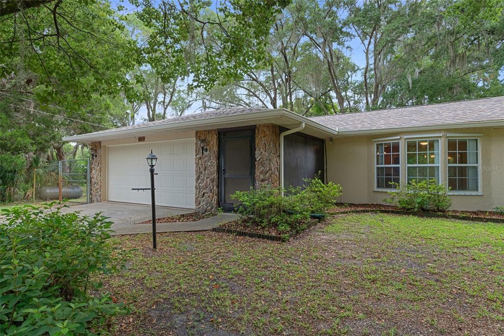 A single-story house with a stone-accented entryway, a two-car garage, and a grassy front yard — 5931 N BROOKGREEN DRIVE, CRYSTAL RIVER, FL