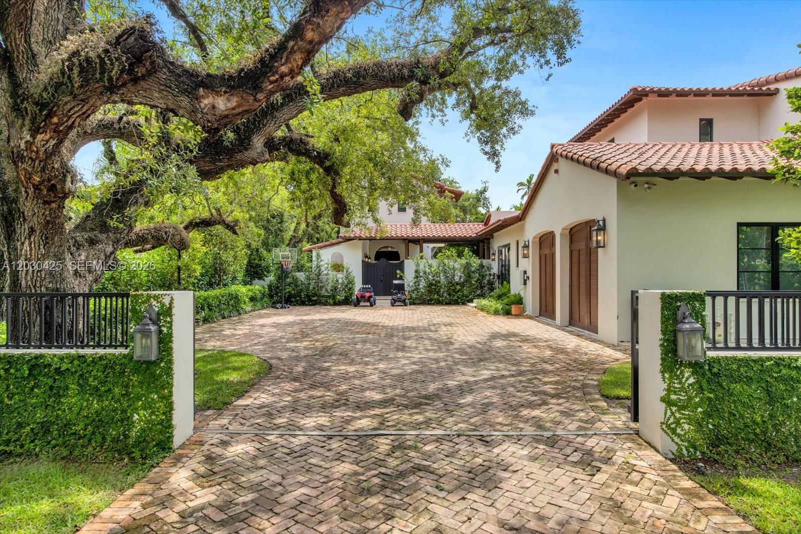 A brick driveway leads to a house with a tile roof and a large tree — 545 San Antonio Ave, Coral Gables FL 33146, CORAL GABLES, FL