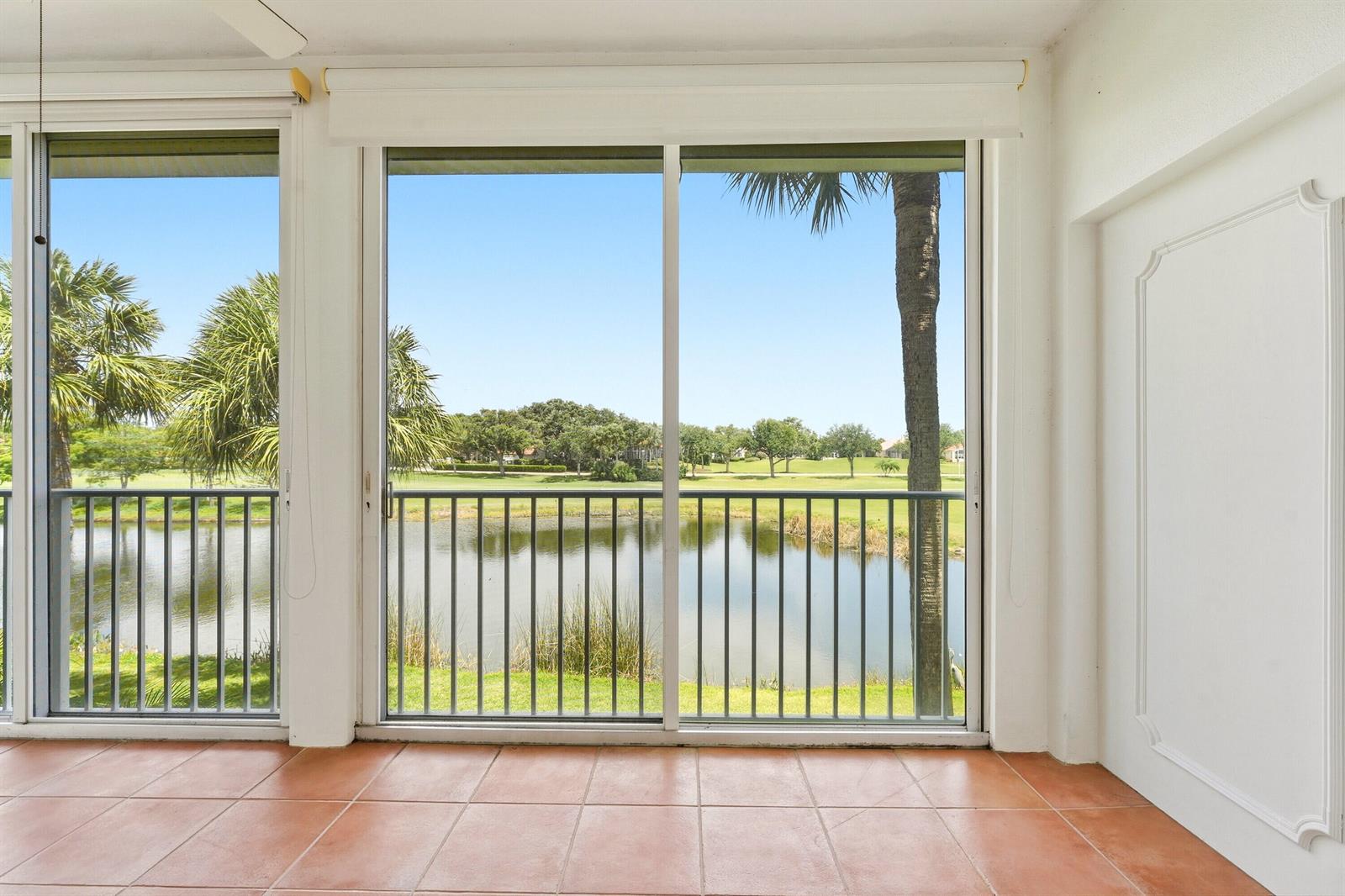 A tiled sunroom features large sliding glass doors overlooking a pond and golf course — 4775 S Harbor Drive # 201, Vero Beach FL 32967, VERO BEACH, FL