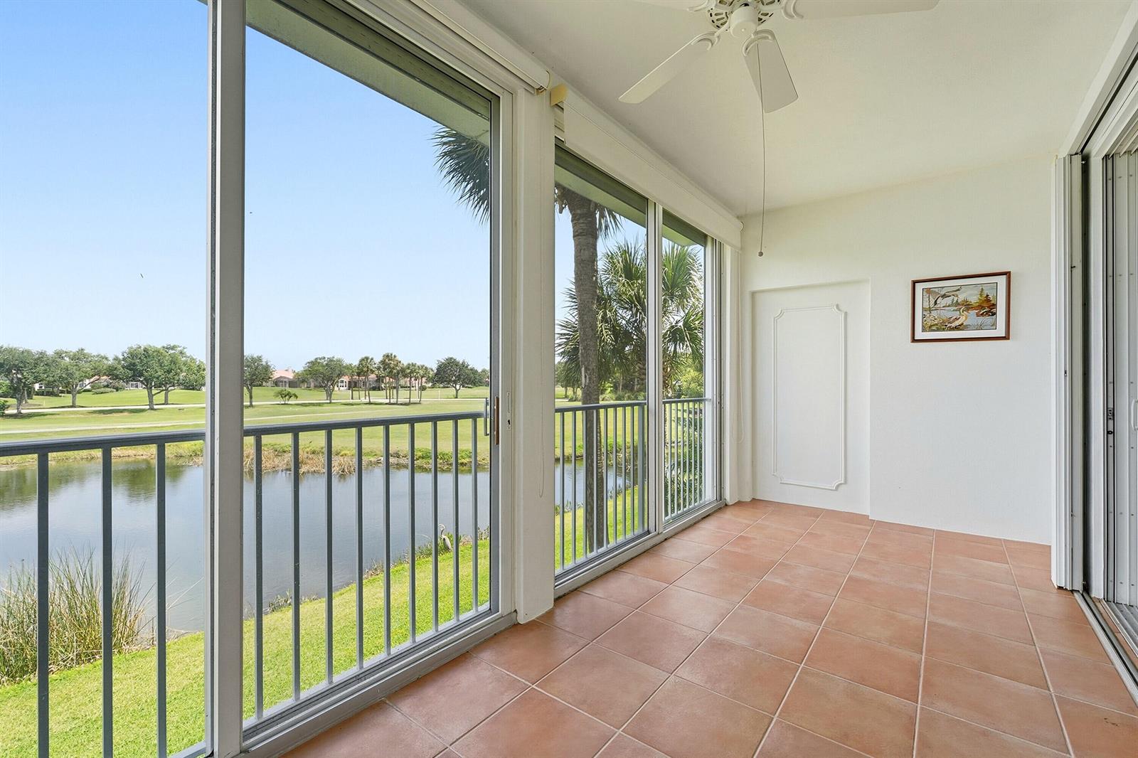 A tiled balcony features sliding glass doors, a ceiling fan, and views of a pond — 4775 S Harbor Drive # 201, Vero Beach FL 32967, VERO BEACH, FL