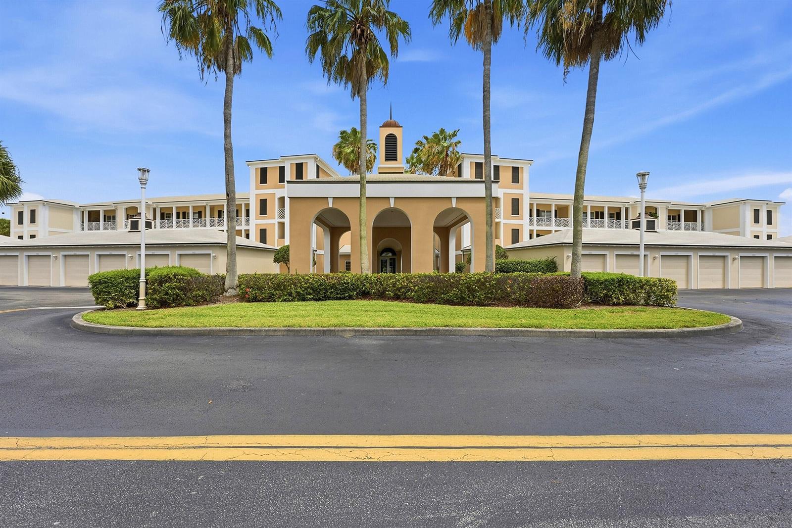 A large, multi-story tan building with a central arched entrance and palm trees in front — 4775 S Harbor Drive # 201, Vero Beach FL 32967, VERO BEACH, FL