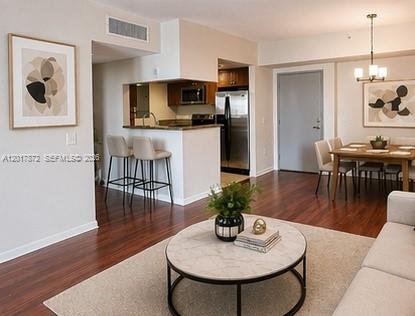 An open-concept living and dining area features hardwood floors, a kitchen island, and modern furniture — 36 NW 6th Ave # 805, Miami FL 33128, MIAMI, FL