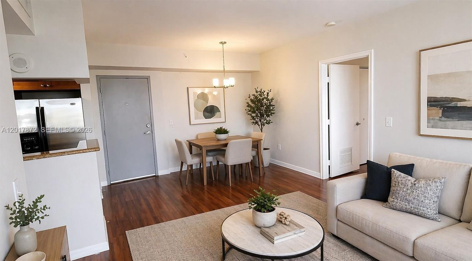 An open-concept living and dining area features wood flooring, a neutral sofa, and a table — 36 NW 6th Ave # 805, Miami FL 33128, MIAMI, FL