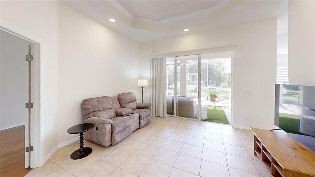 A living room features tile flooring, a reclining sofa, and sliding glass doors to a patio — 8328 SW 84TH PLACE ROAD, OCALA, FL