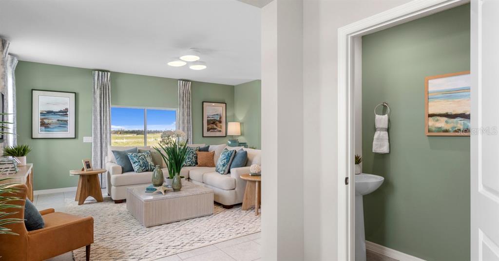 A view from a doorway into a living room with green walls and a powder room — 10136 MORNING MEADOWLARK TRAIL, PARRISH, FL