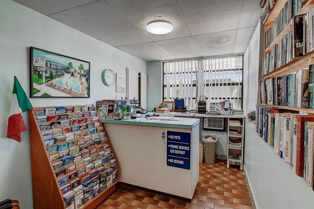 A motel reception area features a brochure rack, a service counter, and a wall of books — 653 MANDALAY AVENUE, CLEARWATER, FL