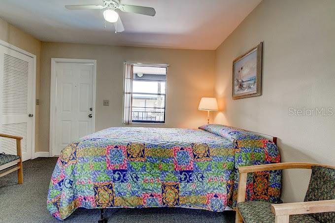 A bedroom features a bed with a colorful patterned quilt, a ceiling fan, and a window — 653 MANDALAY AVENUE, CLEARWATER, FL