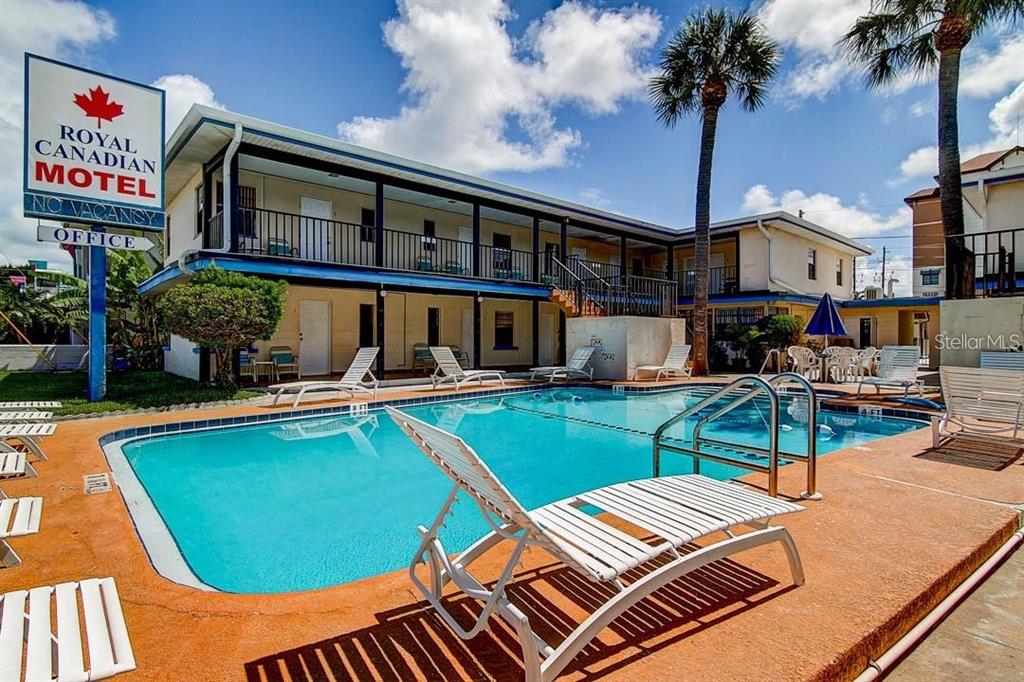 A two-story motel building features a swimming pool with lounge chairs on the patio — 653 MANDALAY AVENUE, CLEARWATER, FL