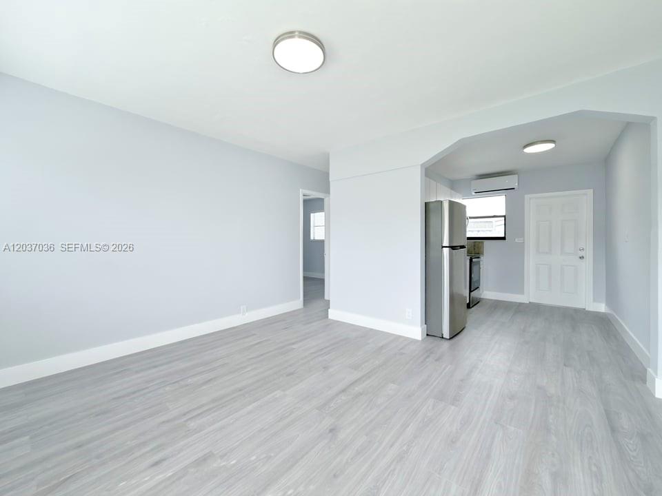 A bright, open-concept living area features light gray walls, wood-look flooring, and an adjacent kitchen — 1010 Opa Locka Blvd # 3, Opa-Locka FL 33054, OPA-LOCKA, FL