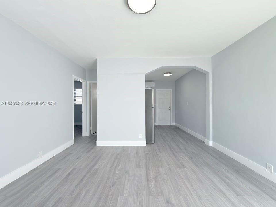 A living area with light gray walls and wood-look flooring leads into a kitchen — 1010 Opa Locka Blvd # 3, Opa-Locka FL 33054, OPA-LOCKA, FL