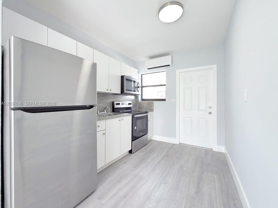 A kitchen features white cabinets, stainless steel appliances, and light wood-look flooring — 1010 Opa Locka Blvd # 3, Opa-Locka FL 33054, OPA-LOCKA, FL