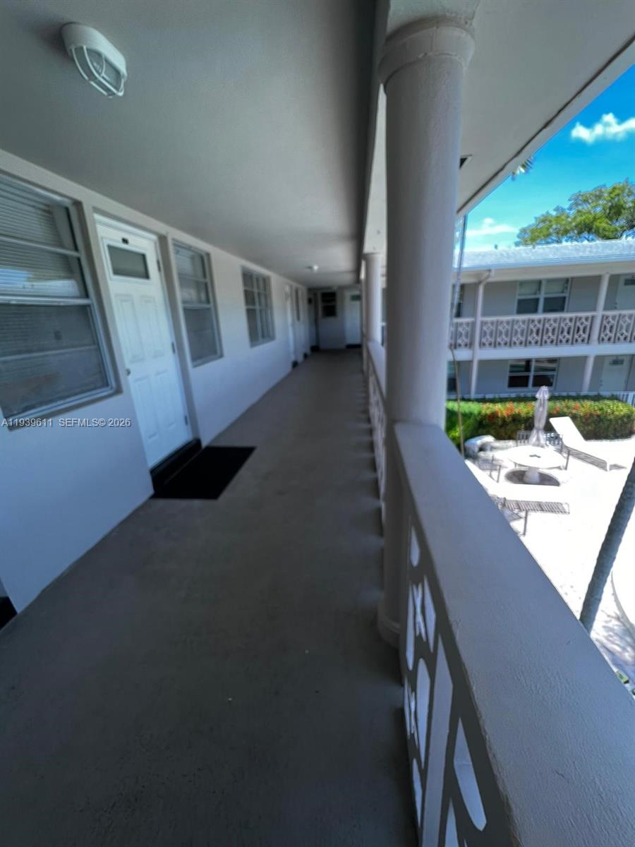 An exterior walkway overlooks a courtyard with a pool and lounge chairs — 2701 NE 1st St # 203, Pompano Beach FL 33062, POMPANO BEACH, FL