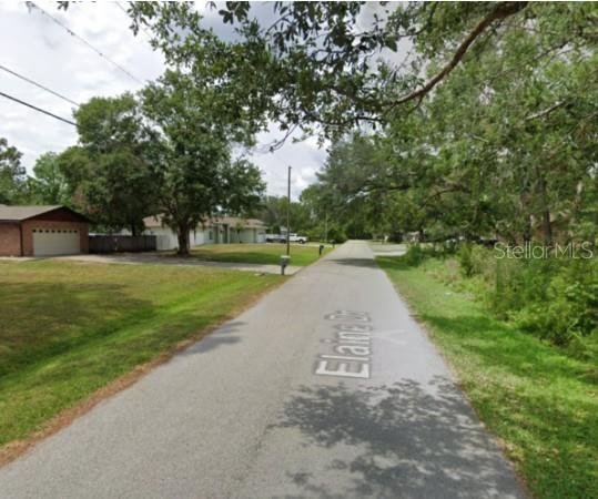 A paved residential street named Elaine Drive is lined with trees and suburban houses — 5728 ELAINE DRIVE, ZEPHYRHILLS, FL