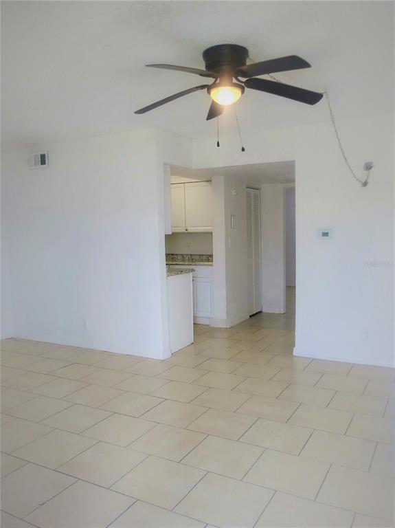 A room with white walls, light-colored tile flooring, and a ceiling fan over the space — 302 S SPRING GARDEN AVENUE UNIT B09, DELAND, FL