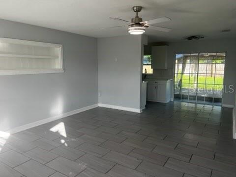 A living room with gray tile flooring, a ceiling fan, and a view of the kitchen — 2522 STRATFORD DRIVE, SARASOTA, FL