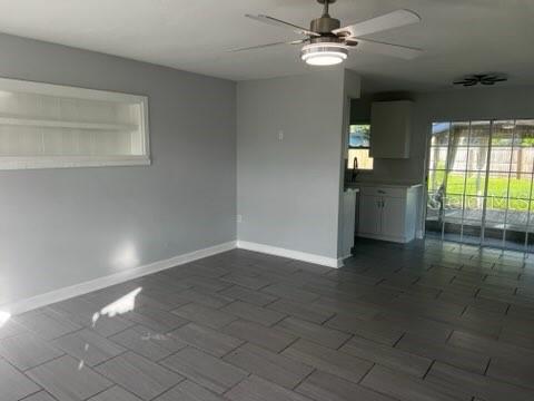 A living room with gray tile flooring, light gray walls, and a ceiling fan — 2522 STRATFORD DRIVE, SARASOTA, FL