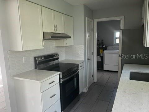 A kitchen with white cabinets, stainless steel appliances, and light countertops leads to a laundry room — 2522 STRATFORD DRIVE, SARASOTA, FL