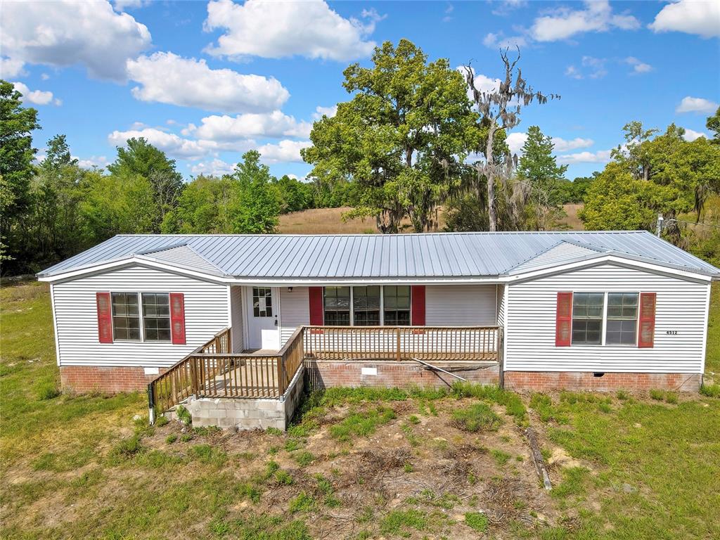 A single-story manufactured home with white siding, a metal roof, and a wooden front deck — 4512 N TIMBERWOOD POINT, CRYSTAL RIVER, FL