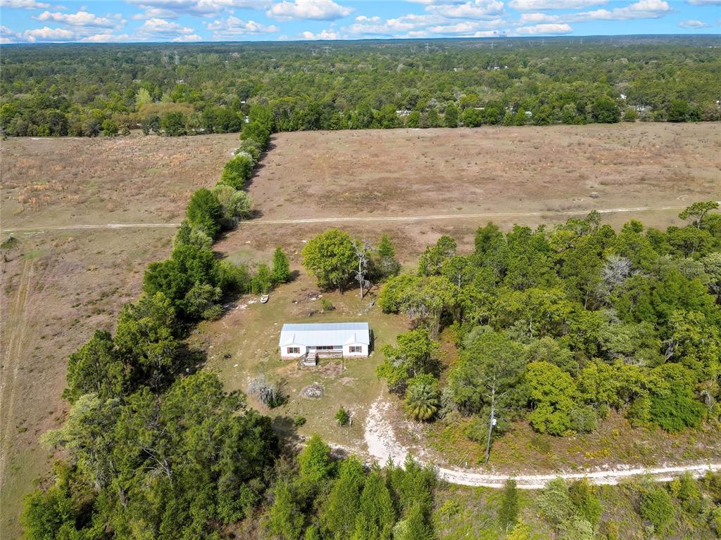 An aerial view shows a single-story house surrounded by trees and large open fields — 4512 N TIMBERWOOD POINT, CRYSTAL RIVER, FL