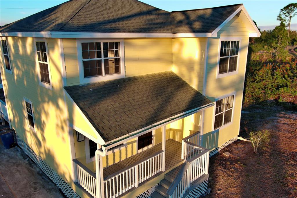 An elevated yellow two-story house features a covered front porch with white railings — 3906 28TH STREET SW, LEHIGH ACRES, FL