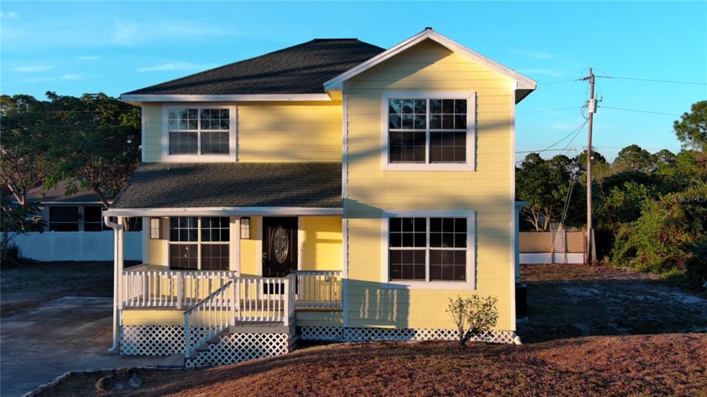 A two-story yellow house with a front porch and lattice skirting stands on a lot — 3906 28TH STREET SW, LEHIGH ACRES, FL