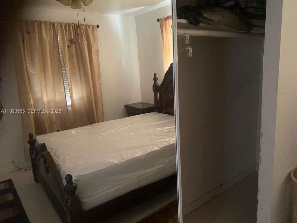 A bedroom features a bed with a dark wood headboard and a mirrored closet door — 712 57th St, West Palm Beach FL 33407, WEST PALM BEACH, FL