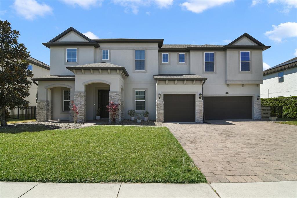 A two-story house with a stucco exterior, stone accents, and a three-car garage — 1250 RED HAVEN LANE, OVIEDO, FL
