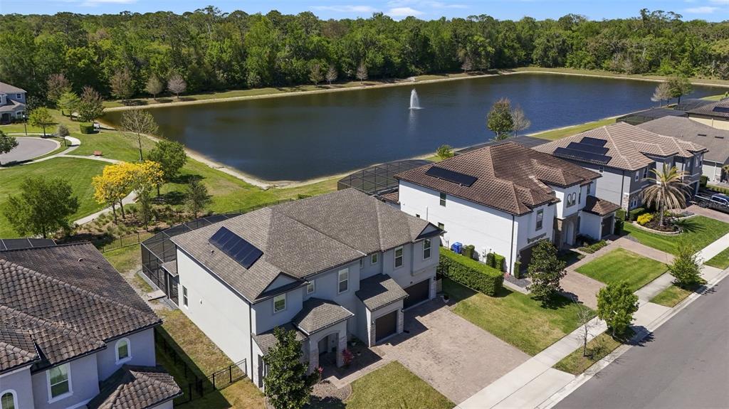 An aerial view shows suburban houses with solar panels near a pond with a fountain — 1250 RED HAVEN LANE, OVIEDO, FL