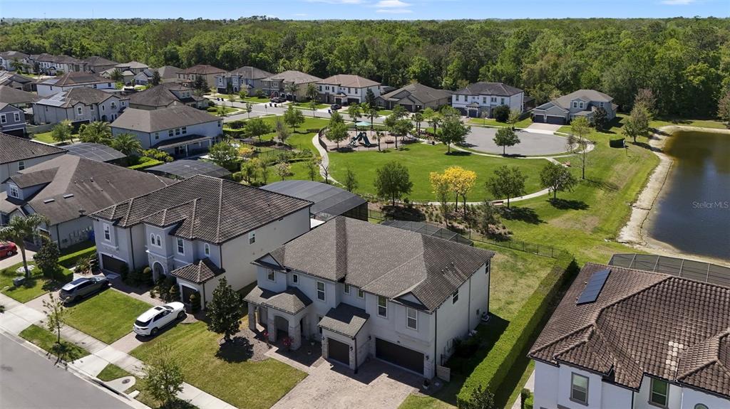 An aerial view shows suburban houses surrounding a central park with a playground and pond — 1250 RED HAVEN LANE, OVIEDO, FL