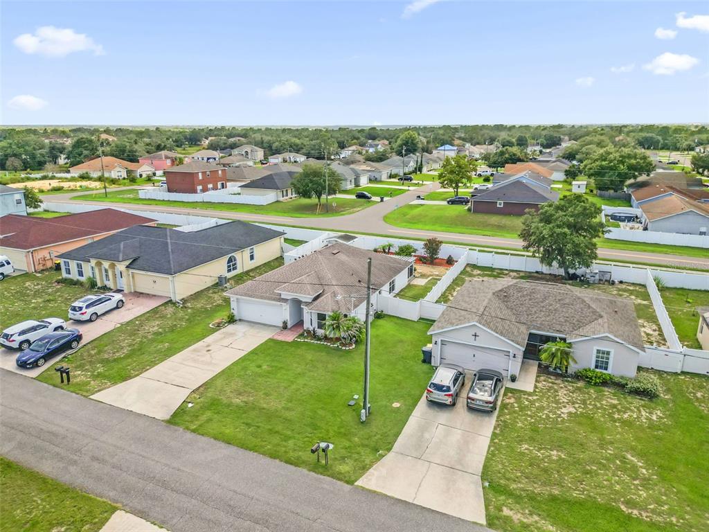 An aerial view shows three suburban houses with driveways and lawns in a residential neighborhood — 1747 POMPANO DRIVE, KISSIMMEE, FL