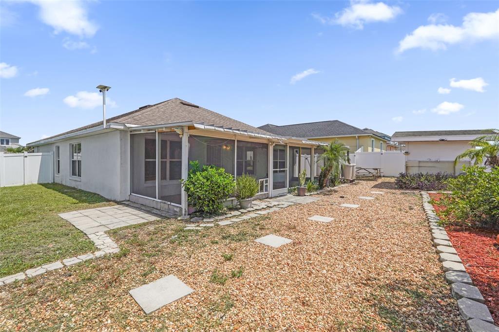 The exterior of a house features a screened-in porch and a gravel backyard — 1747 POMPANO DRIVE, KISSIMMEE, FL