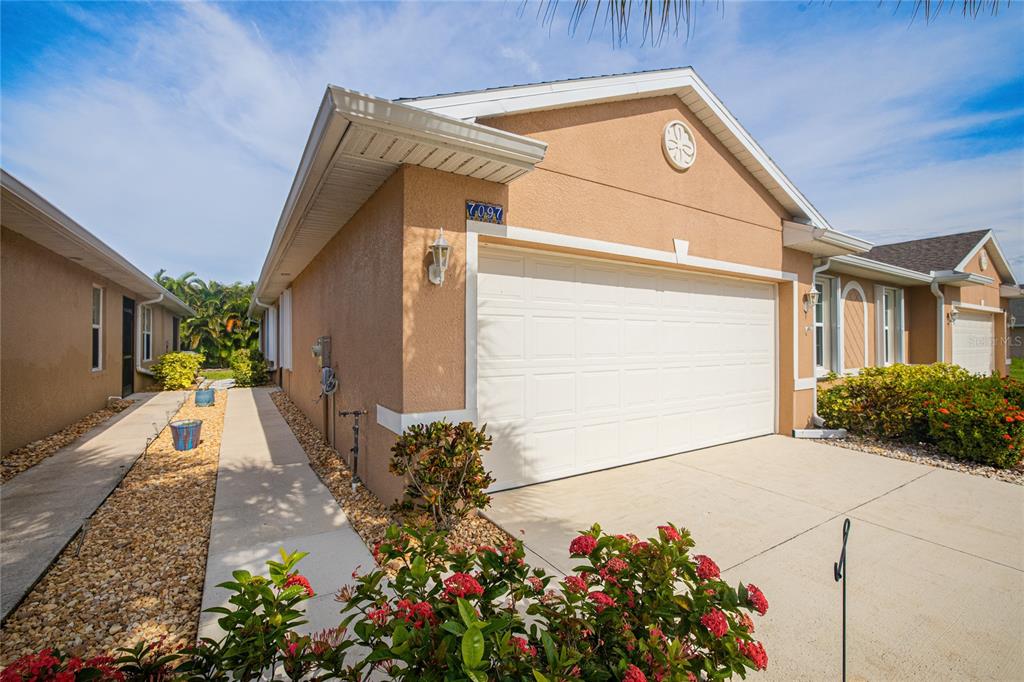 A tan stucco house with a white garage door and a concrete driveway — 7097 W LENOX CIRCLE, PUNTA GORDA, FL