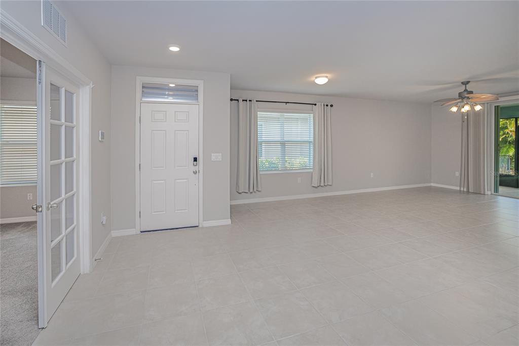 An open living area features light tile flooring, a white front door, and a ceiling fan — 7097 W LENOX CIRCLE, PUNTA GORDA, FL