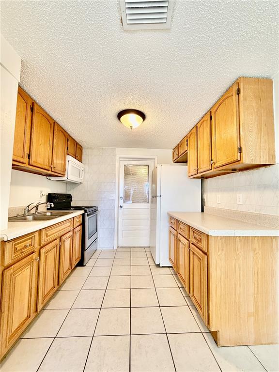 A galley kitchen features light wood cabinets, white countertops, tile flooring, and a white refrigerator — 2204 IRENE STREET UNIT B, LUTZ, FL