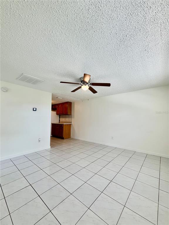 An open-concept room with white tile flooring, a ceiling fan, and a small kitchen area — 2204 IRENE STREET UNIT B, LUTZ, FL