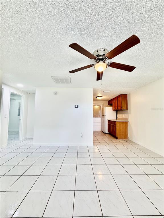 A room with white tiled floors, a ceiling fan, and a view into a kitchen — 2204 IRENE STREET UNIT B, LUTZ, FL