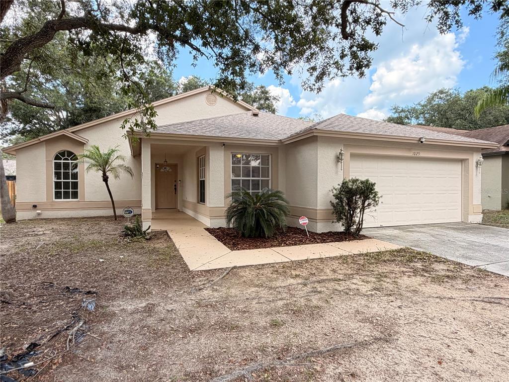 A single-story house with a beige stucco exterior, a two-car garage, and a front walkway — 1025 MALLETWOOD DRIVE, BRANDON, FL