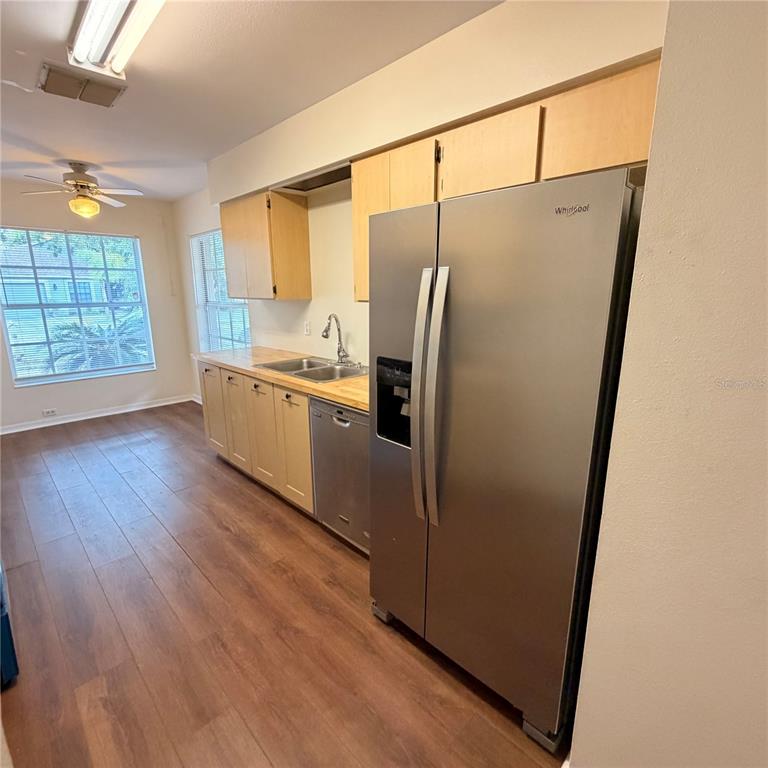 A kitchen features light wood cabinets, stainless steel appliances, and wood-look flooring — 1025 MALLETWOOD DRIVE, BRANDON, FL