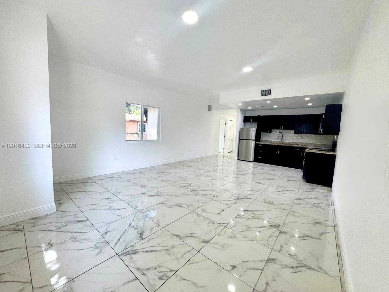 An open-concept living area features white walls, marble-patterned tile flooring, and a modern kitchen — 7703 NW 3rd Ave, Miami FL 33150, MIAMI, FL