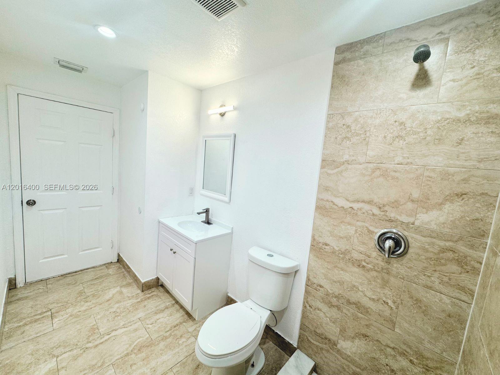 A bathroom features a white vanity, a toilet, and a tiled walk-in shower — 7703 NW 3rd Ave, Miami FL 33150, MIAMI, FL