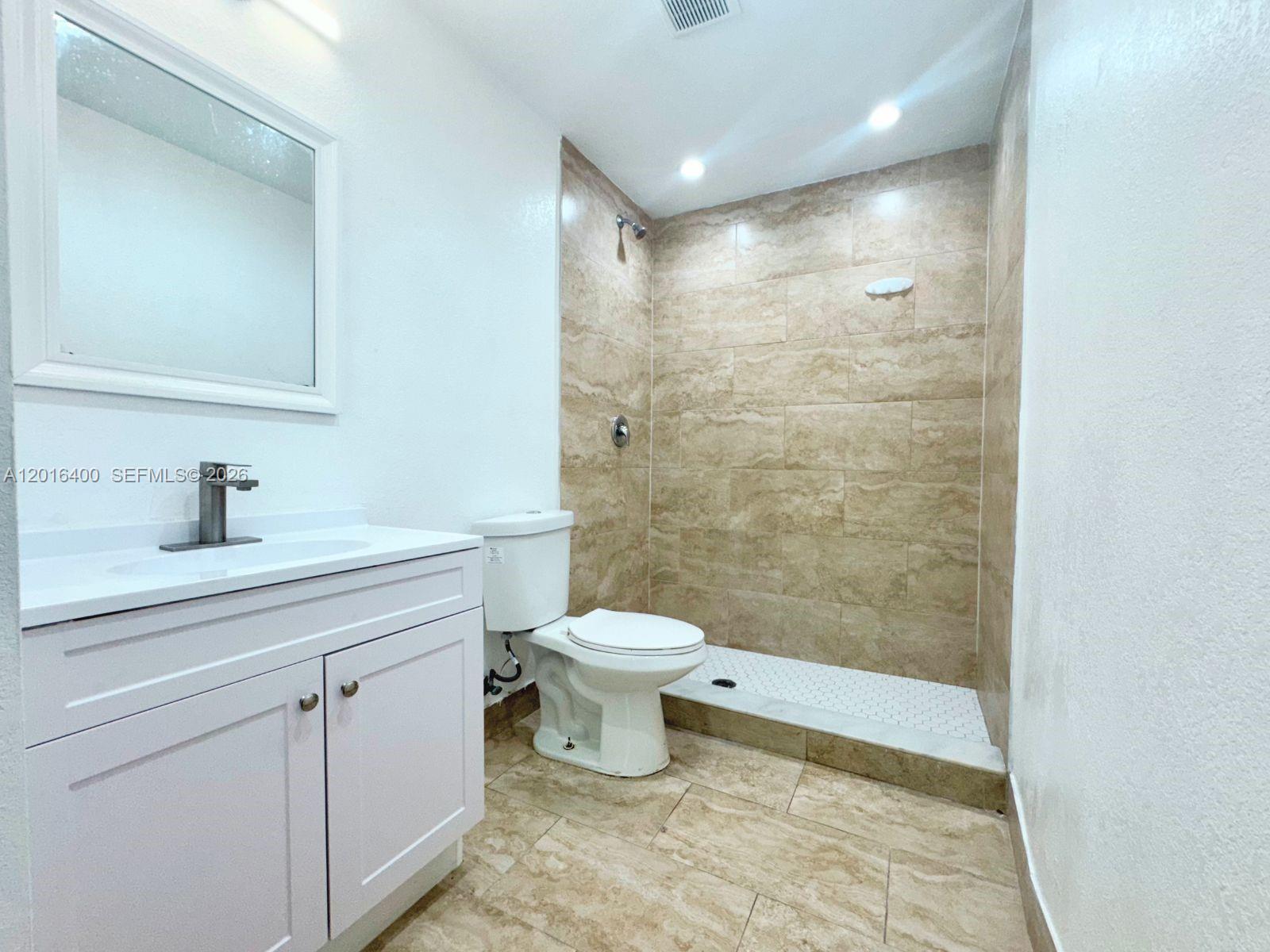 A bathroom features a white vanity, a toilet, and a walk-in shower with tiled walls — 7703 NW 3rd Ave, Miami FL 33150, MIAMI, FL